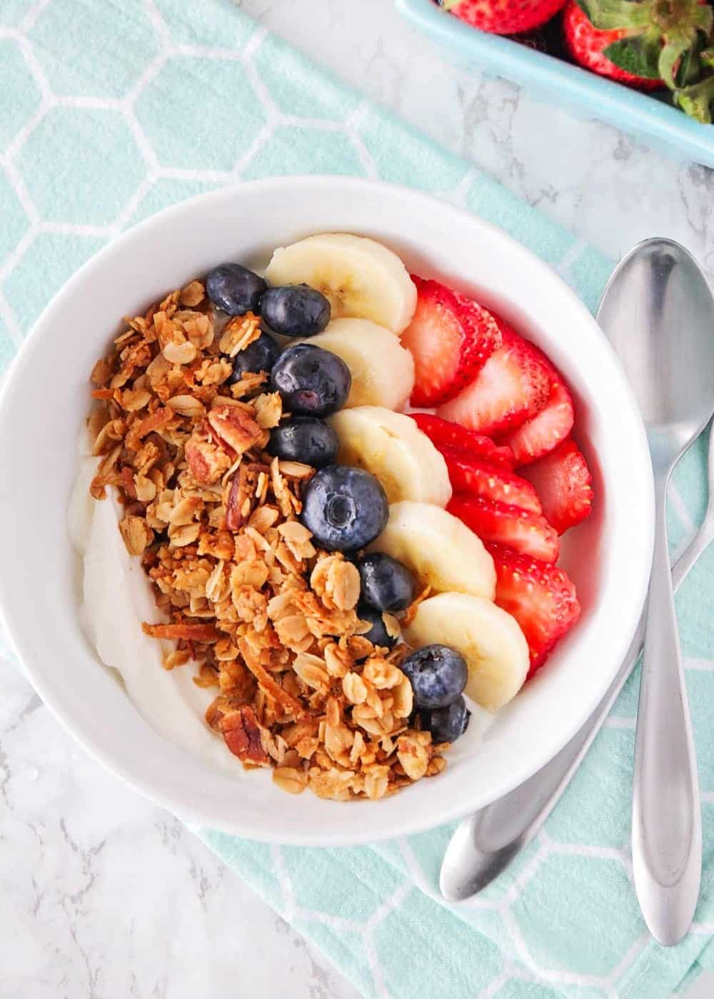 Bowl of yogurt topped with homemade granola and fresh fruit.