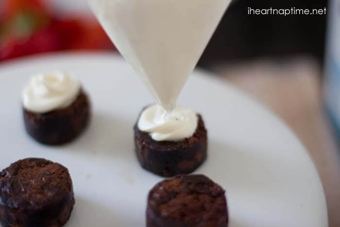 Piping frosting on top of brownie bites.