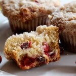 A close up of a crumb topped cranberry eggnog muffin sliced in half