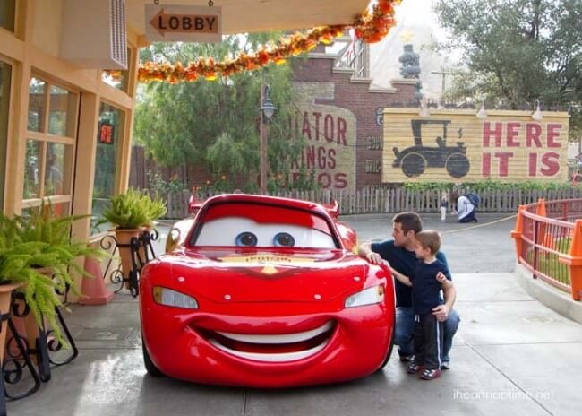 a man and boy looking at a red car 