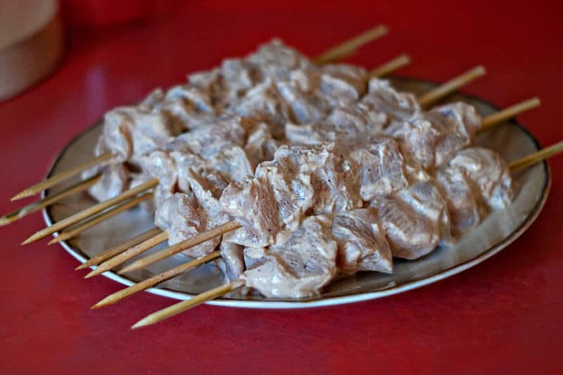 a plate with raw chicken skewers on it 
