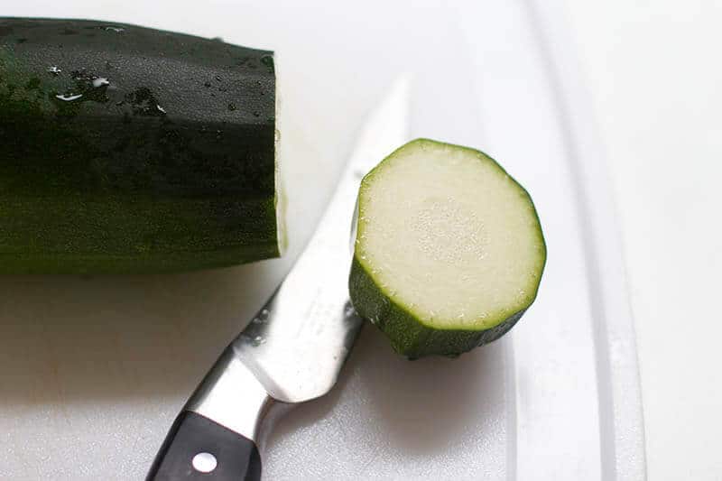 Slicing zucchini on a cutting board.