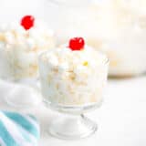 ambrosia salad in a trifle dish with a cherry on top