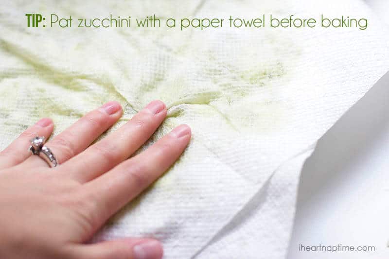 Patting down on shredded zucchini with a paper towel.