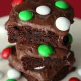 A close up of a stack of frosted holiday mint M&M brownies