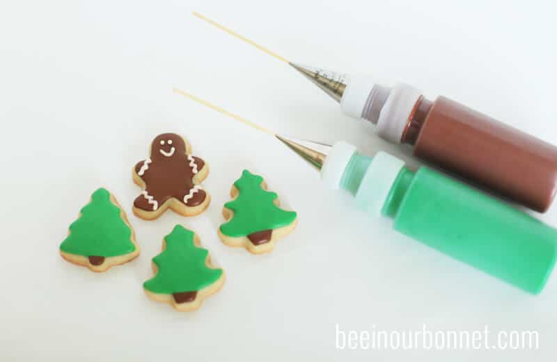 christmas sugar cookies sitting on counter with 2 bottles of icing 