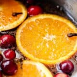 A close up of stovetop potpourri with fresh orange slices and cranberries