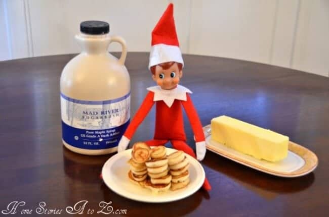 Elf sitting by a plate of mini pancakes.