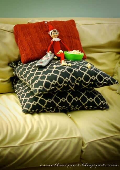 Elf eating popcorn on top of pillows.