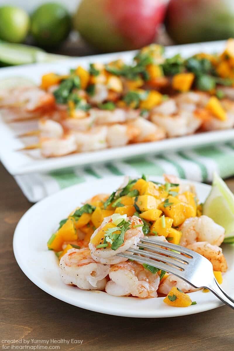 eating grilled shrimp and mango salsa on a plate with a fork 
