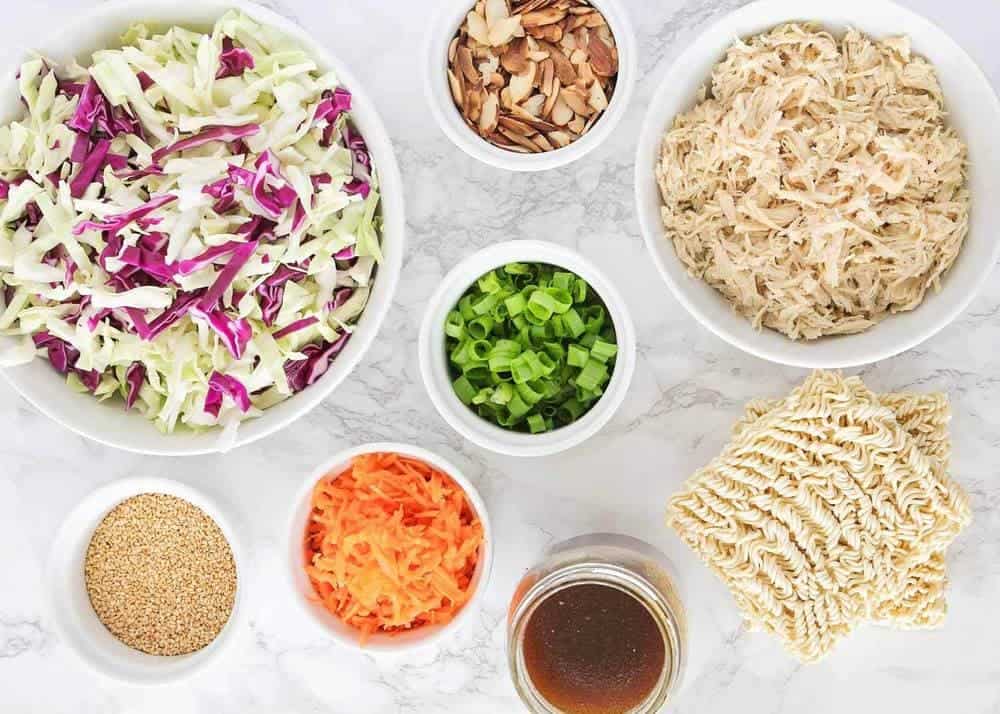 Ingredients for ramen cabbage salad in bowls on the counter.