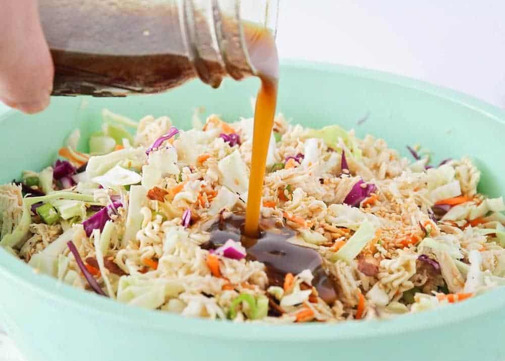Pouring dressing on top of ramen noodle salad.