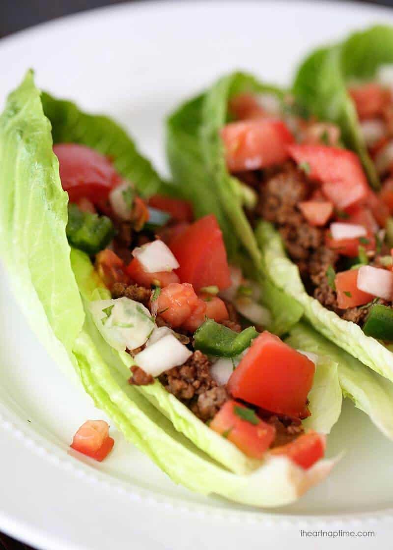 Lettuce tacos on a white plate topped with pico de gallo.