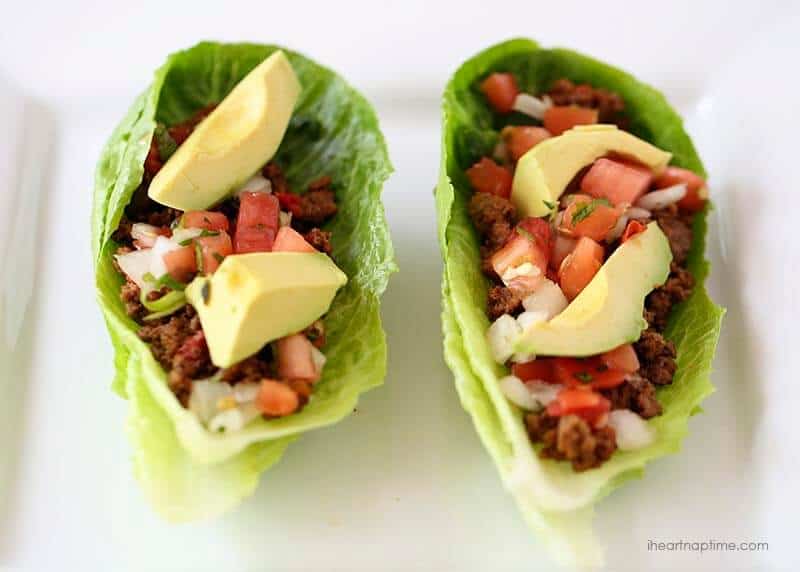 Two taco lettuce wraps topped with pico de gallo and sliced avocado.