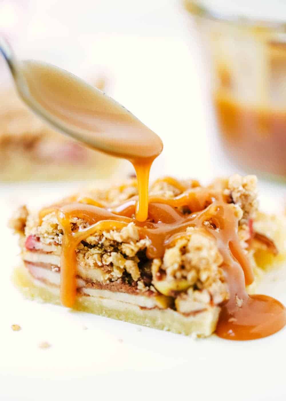 Drizzling caramel over an apple pie bar with a spoon.