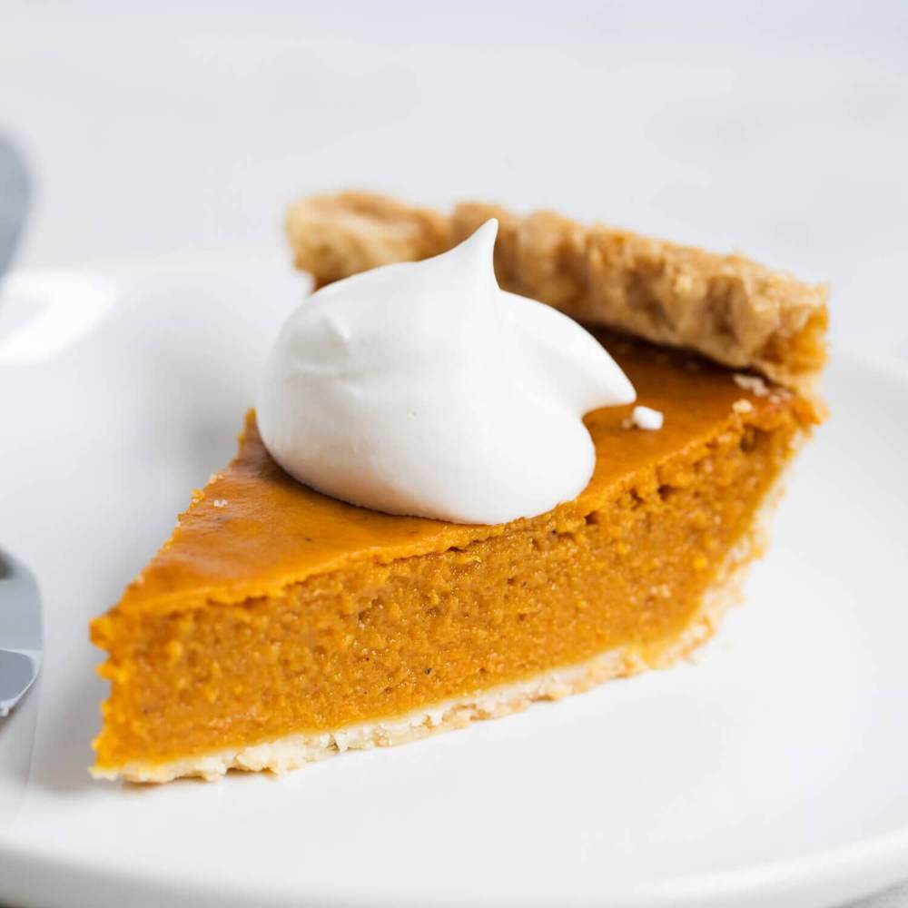 Slice of pumpkin pie with homemade whipped cream on top.