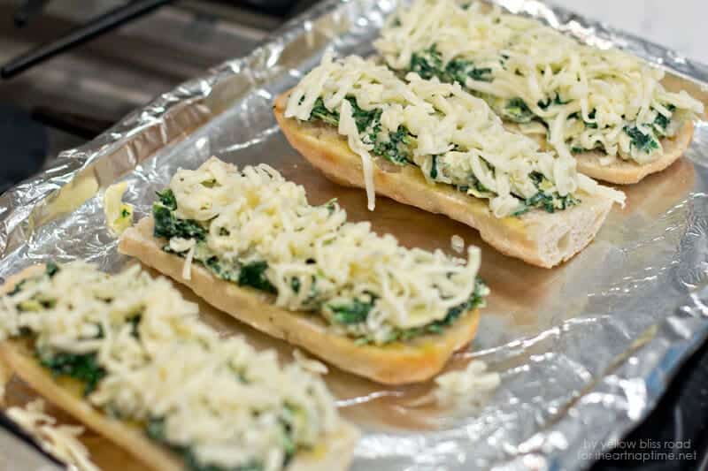 spinach artichoke french bread pizza on foil lined baking sheet 
