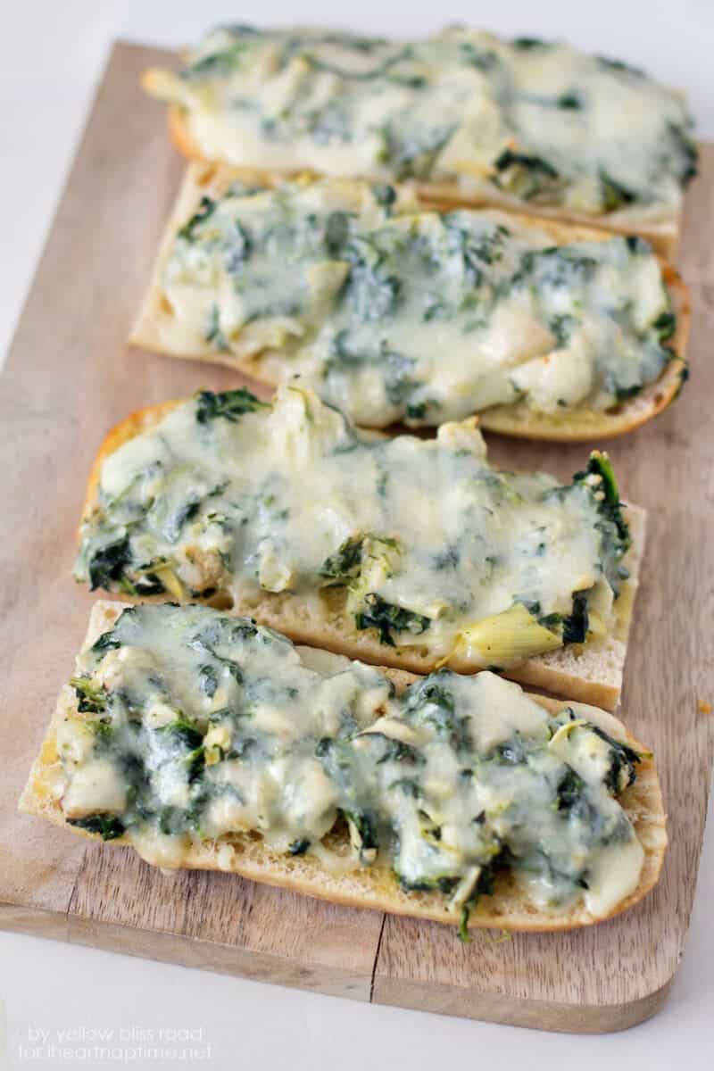 spinach artichoke french bread pizzas on wood table 