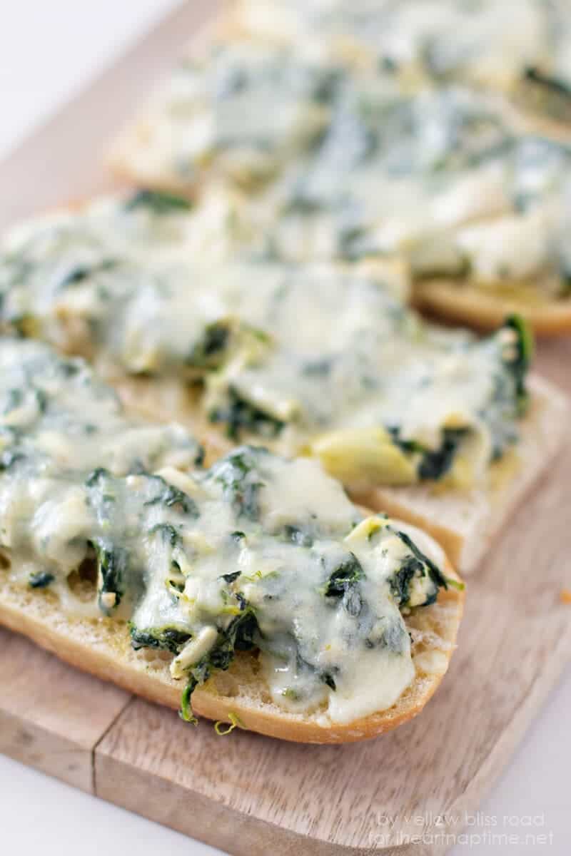close up of spinach artichoke french bread pizza on wood table 