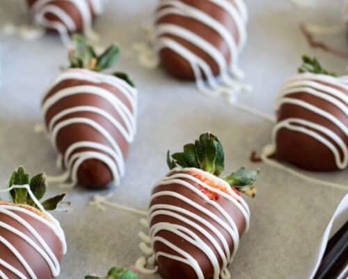 chocolate covered strawberries on a baking sheet with wax paper