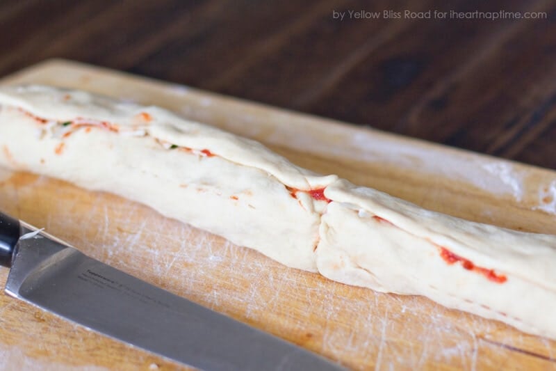 Pizza-Pinwheel-Rolle auf einem Schneidebrett mit einem Messer