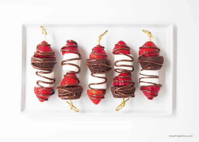 Chocolate strawberry dessert kabobs on a white serving plate.