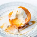 baked peach on a plate with ice cream on top