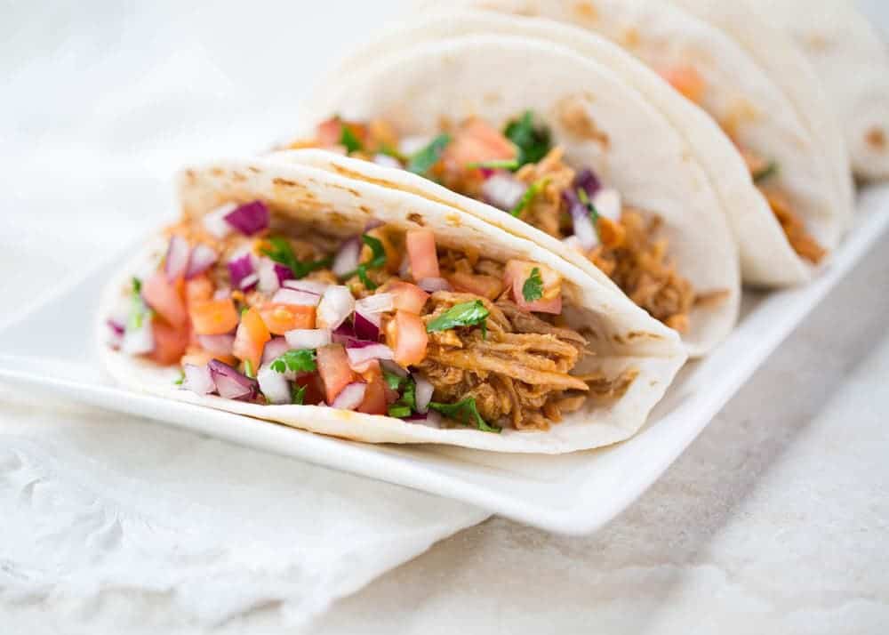 Sweet pork tacos on a white plate. 
