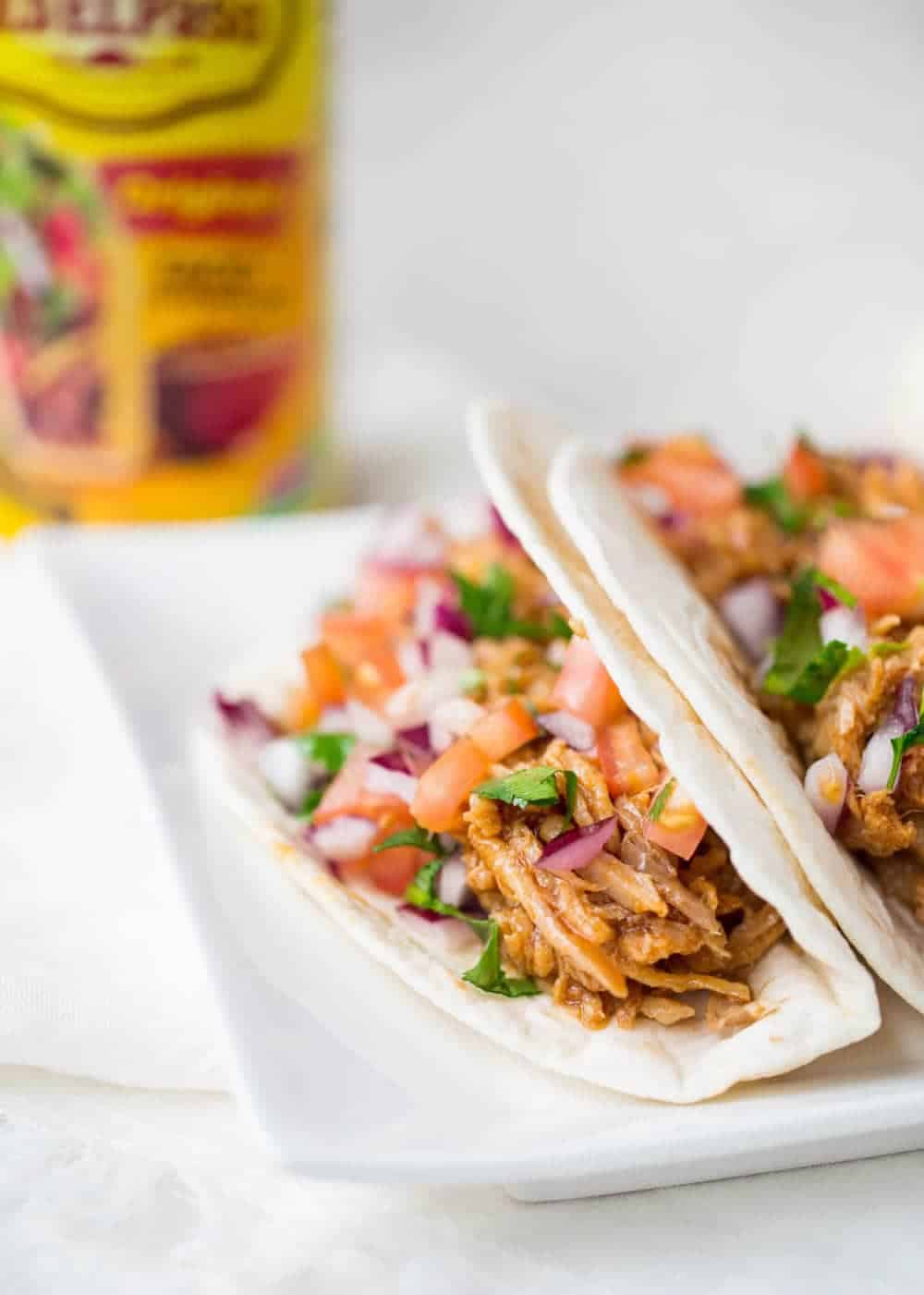 Pulled pork tacos on a white plate. 