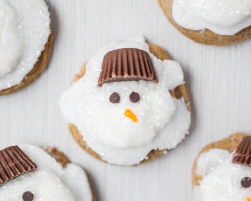 Melted Ginger Snowman Cookies - with a marshmallow belly, Reese's Peanut Butter Cup hat and chocolate chips for the eyes. Such a creative and kid-friendly dessert for the holidays!