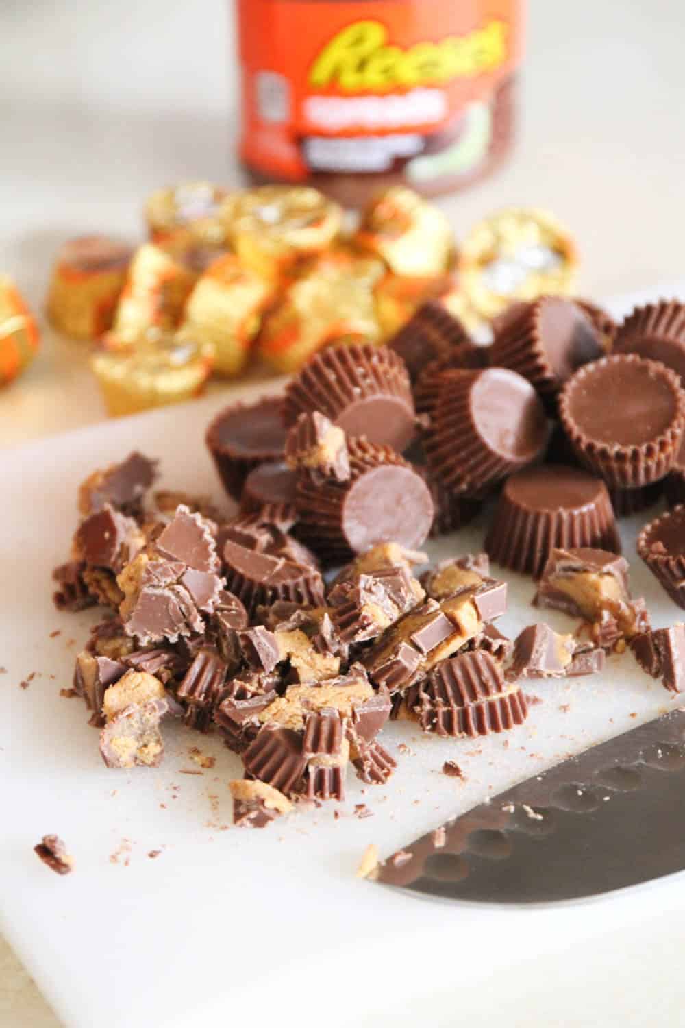 Chopping Reese's cups with a knife on a cutting board.