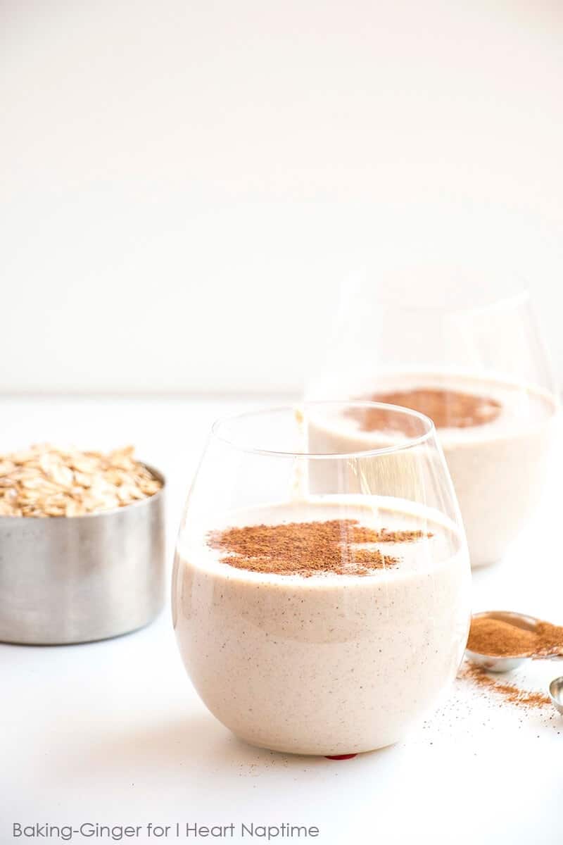 cinnamon roll smoothie in a glass with cinnamon sprinkled on top 