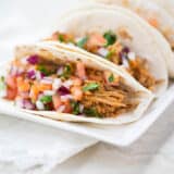 sweet pork tacos on a white plate