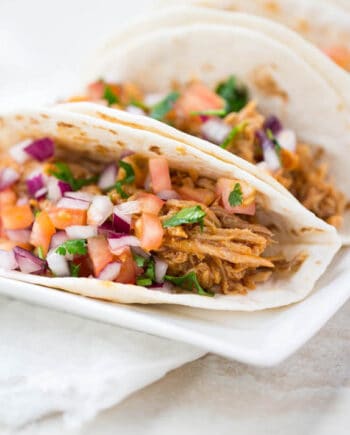 sweet pork tacos on a white plate