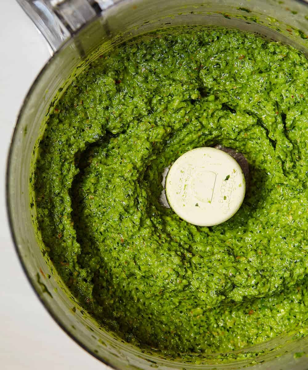 A close up of pesto in a food processor.