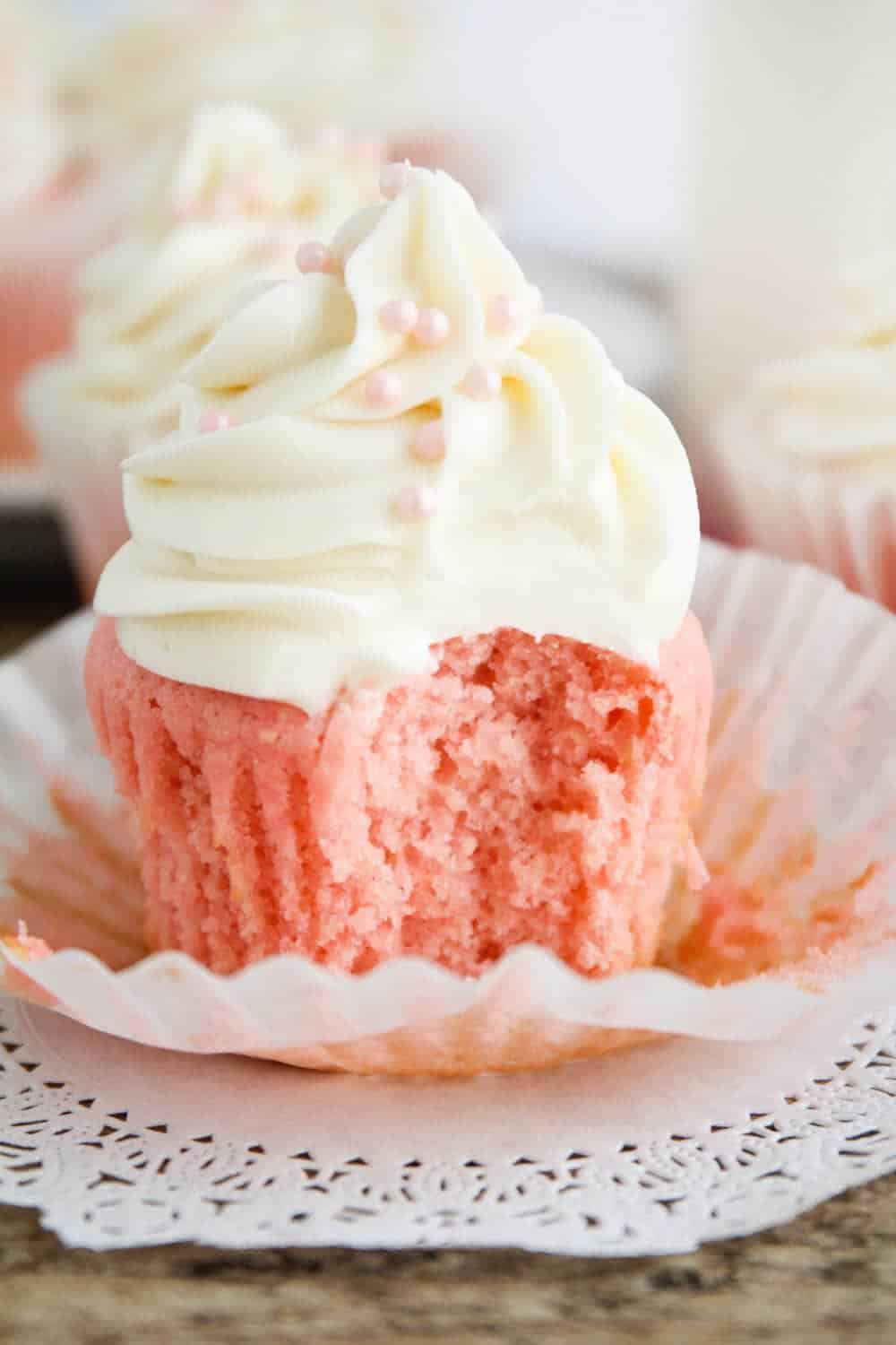 Pink velvet cupcake with a bite taken out.