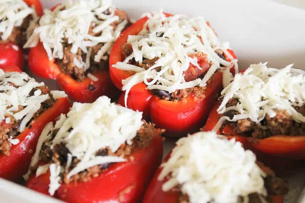 Quinoa stuffed bell peppers with shredded cheese on top.