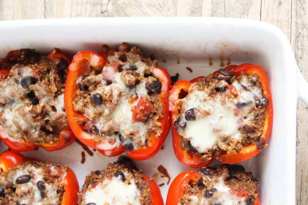 Quinoa stuffed bell peppers in a white baking dish. 
