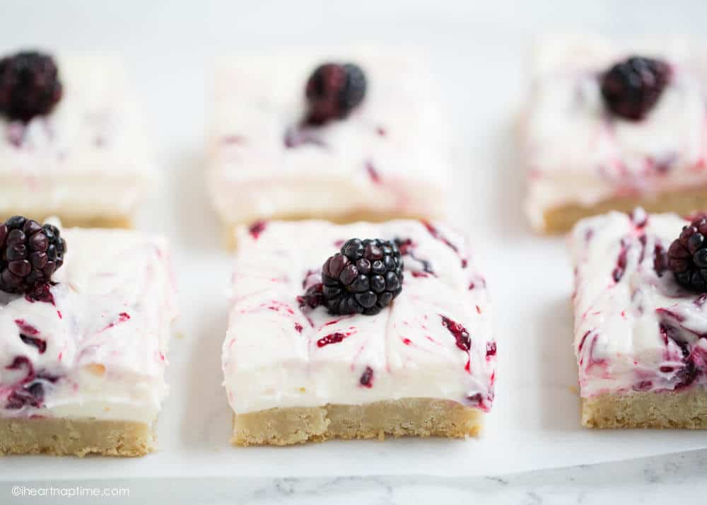 Blackberry cheesecake bars with a fresh blackberry on top.