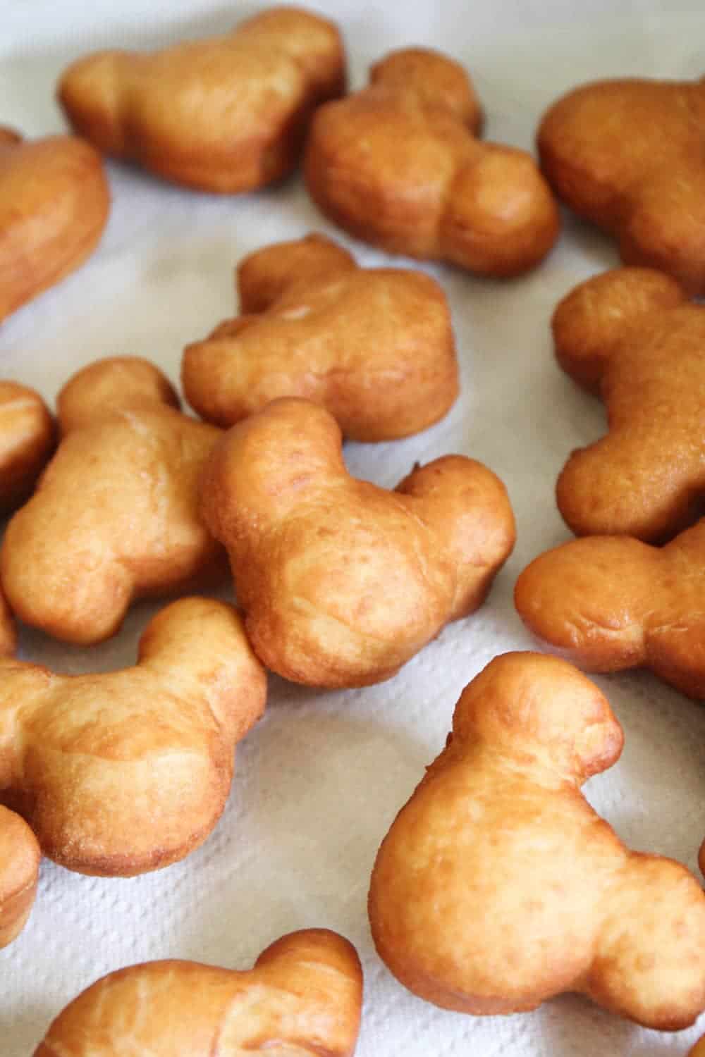 Mickey mouse beignets cooling on a paper towel.