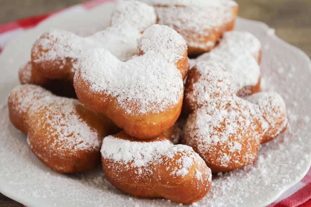 Mickey mouse beignets on a white plate.