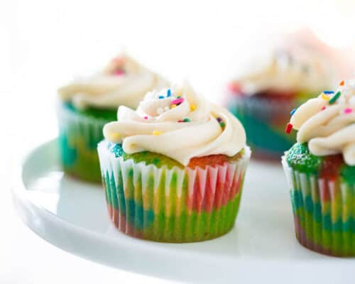 EASY rainbow cupcakes made with a doctored cake mix recipe and buttercream frosting! Everyone loved these!