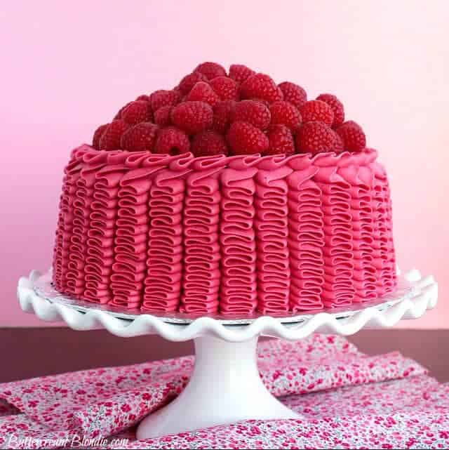 pink raspberry lemon ruffle cake on a white cake stand 