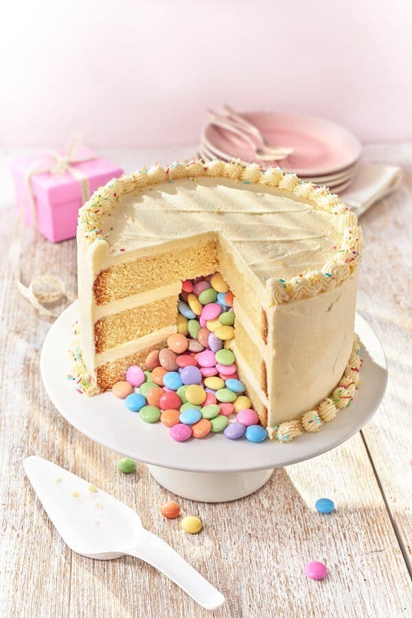 a cake cut open on a cake stand with candy pouring out 