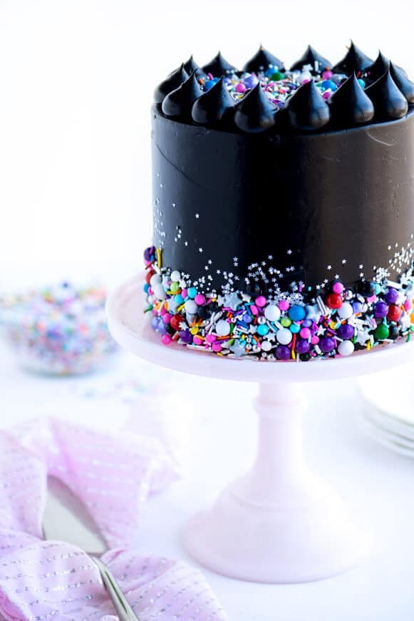 black cake with sprinkles on a cake stand 