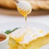 drizzling honey onto baked brie with a honey dipper