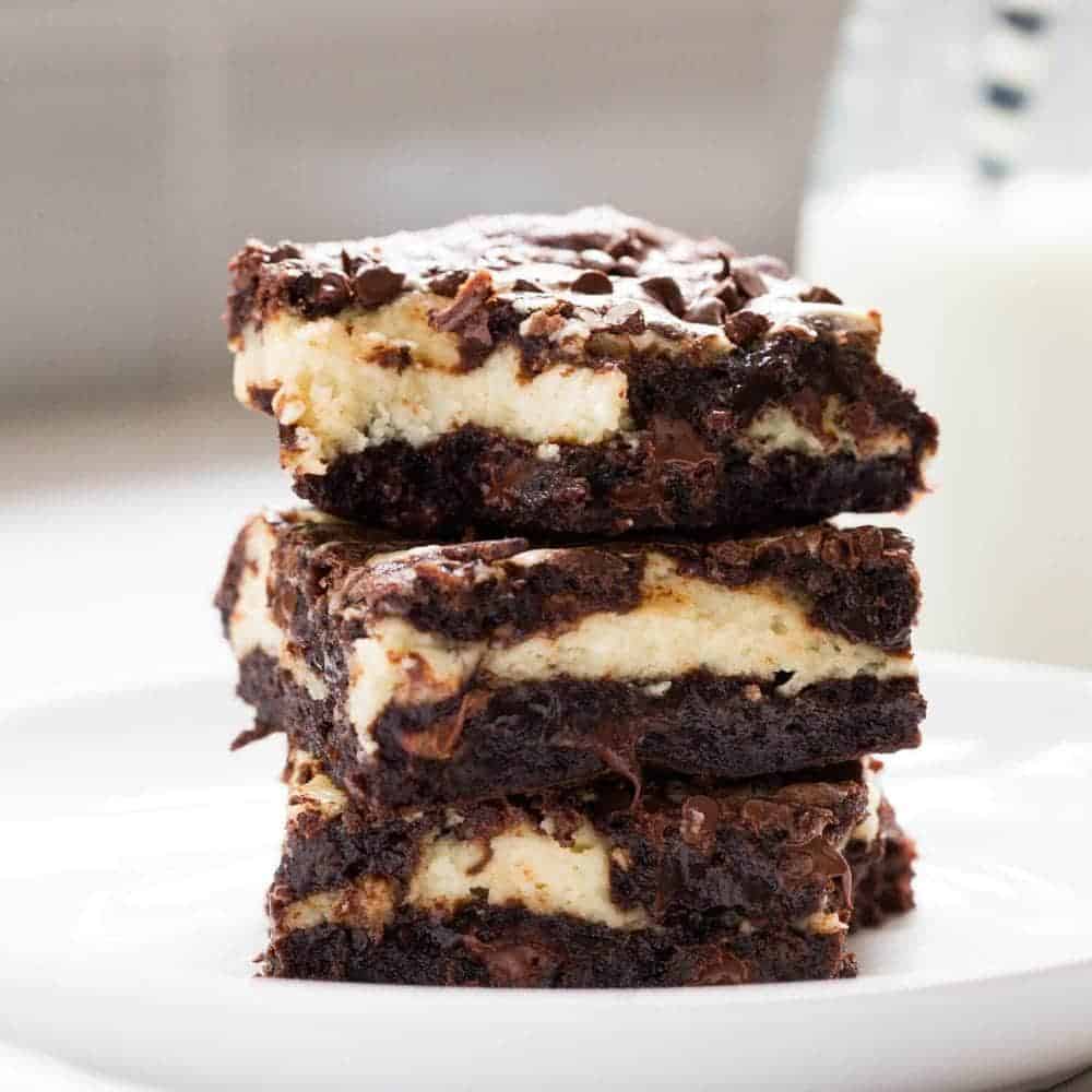 Fudgy cheesecake brownies swirled with a cream cheese filling and chocolate chips. Super soft, rich and the ultimate chocolate lover's dream dessert! Stack of cheesecake brownies.