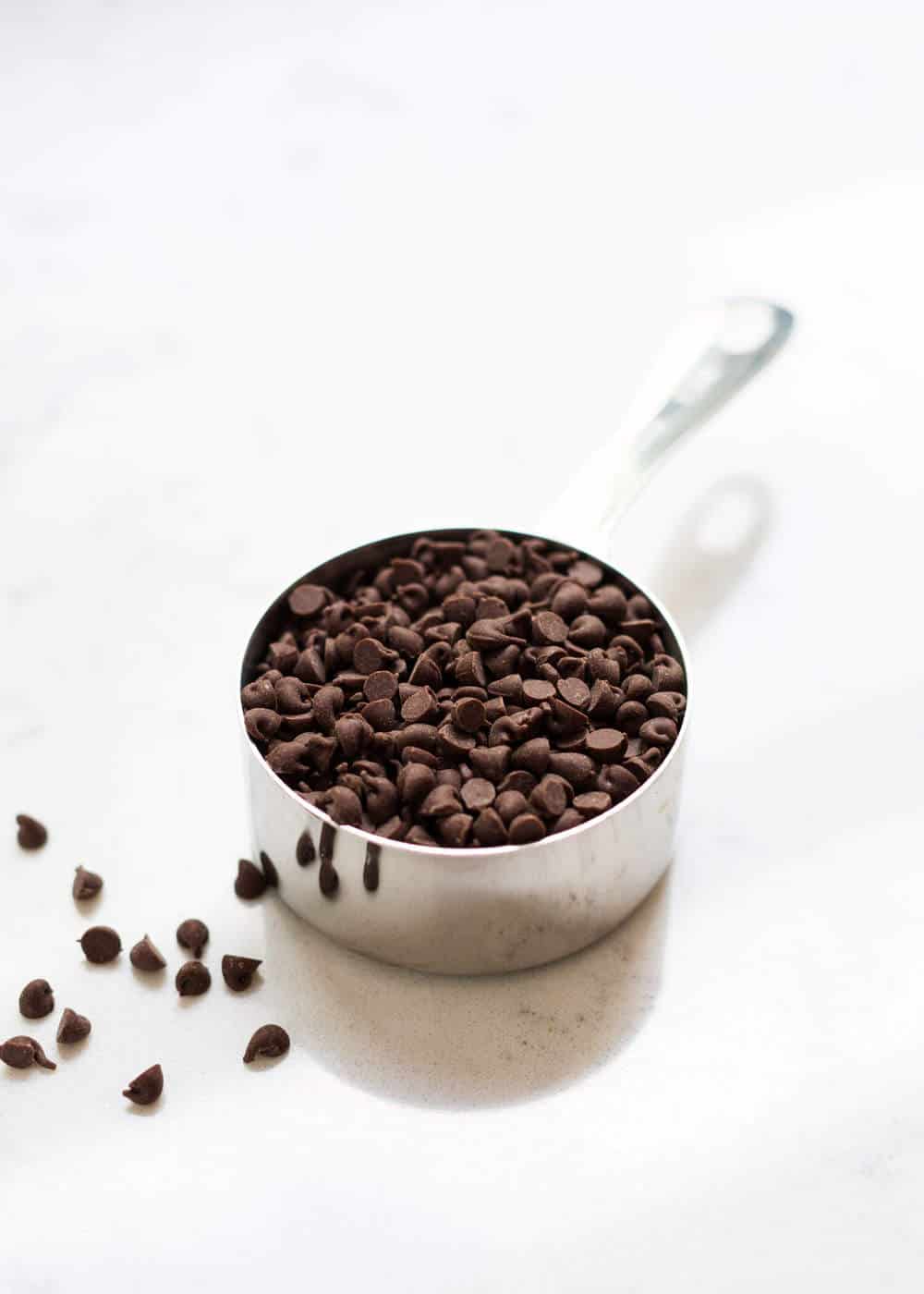 Silver measuring cup filled with chocolate chips.