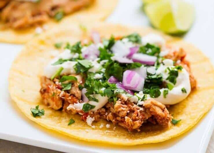 Chicken tinga taco topped with cilantro and red onion.