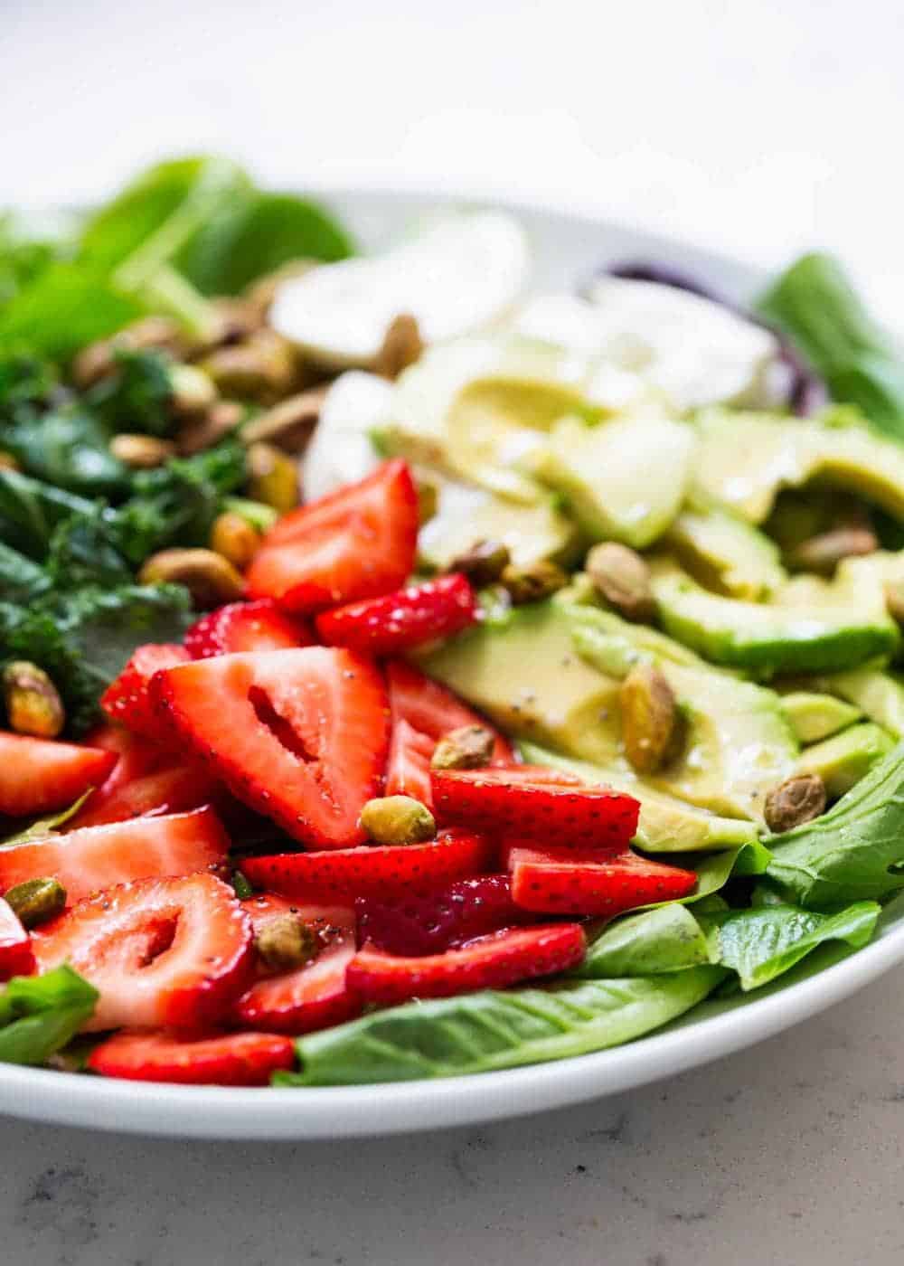 Strawberry salad with burrata cheese, sliced avocado and pistachios.